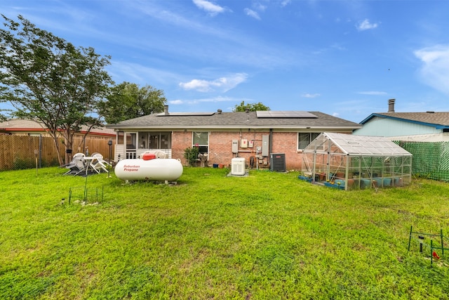 back of property featuring solar panels, a yard, and central air condition unit