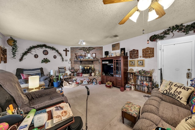 carpeted living room with ceiling fan, a brick fireplace, and a textured ceiling