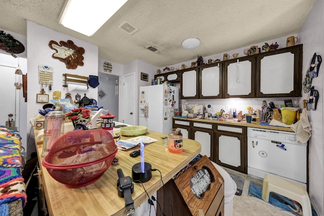 kitchen featuring a textured ceiling, white appliances, dark brown cabinets, and light tile flooring