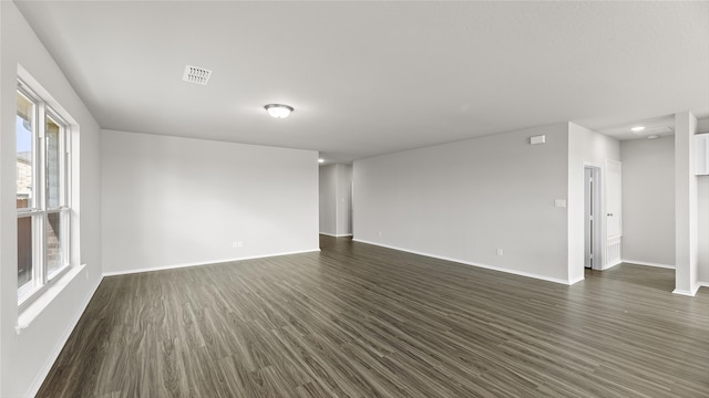 empty room with a wealth of natural light and dark hardwood / wood-style flooring