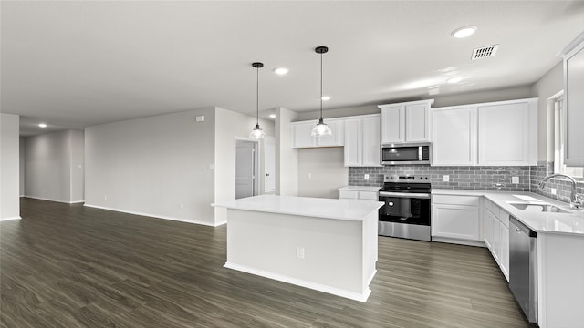 kitchen with a center island, sink, white cabinetry, stainless steel appliances, and dark hardwood / wood-style flooring