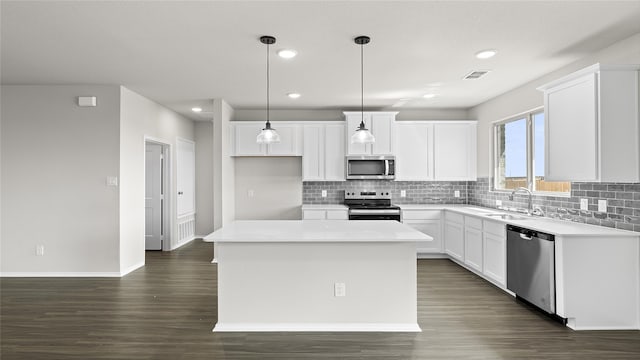 kitchen featuring white cabinetry, a kitchen island, stainless steel appliances, decorative light fixtures, and sink