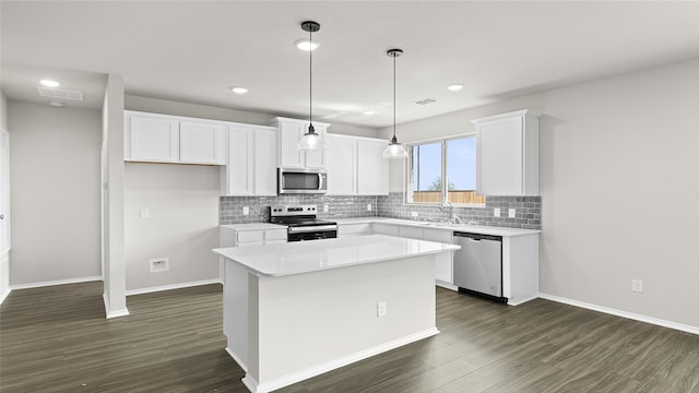 kitchen featuring a center island, dark wood-type flooring, white cabinetry, stainless steel appliances, and decorative light fixtures