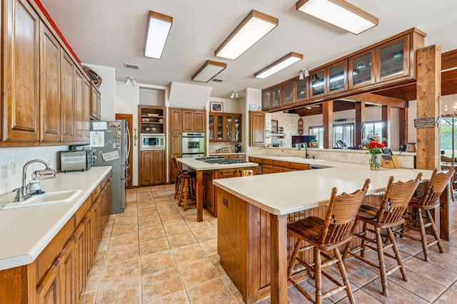 kitchen featuring sink, kitchen peninsula, light tile floors, and a breakfast bar