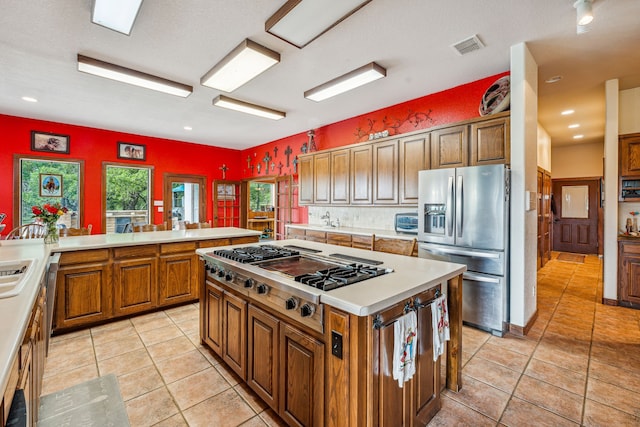 kitchen with a center island, appliances with stainless steel finishes, a textured ceiling, and light tile floors