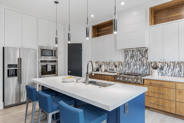 kitchen with appliances with stainless steel finishes, tasteful backsplash, pendant lighting, and a kitchen island with sink