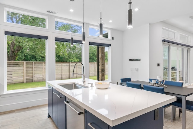 kitchen with light hardwood / wood-style floors, dishwasher, an island with sink, sink, and pendant lighting