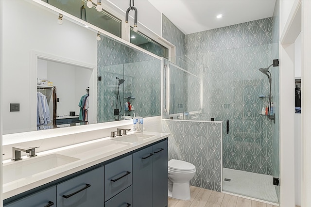 bathroom with double sink vanity, toilet, a shower with door, and hardwood / wood-style flooring