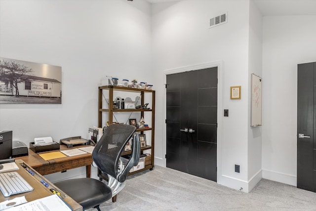 office area with carpet floors and a towering ceiling