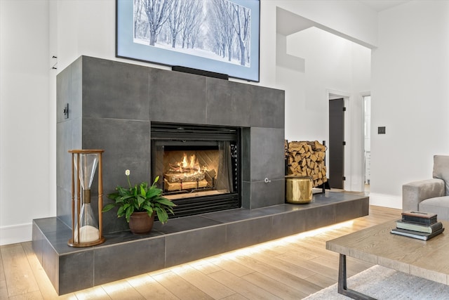 interior details featuring wood-type flooring and a tiled fireplace