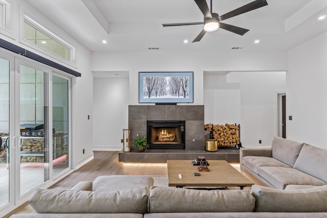 living room with a wealth of natural light, hardwood / wood-style flooring, ceiling fan, and a fireplace