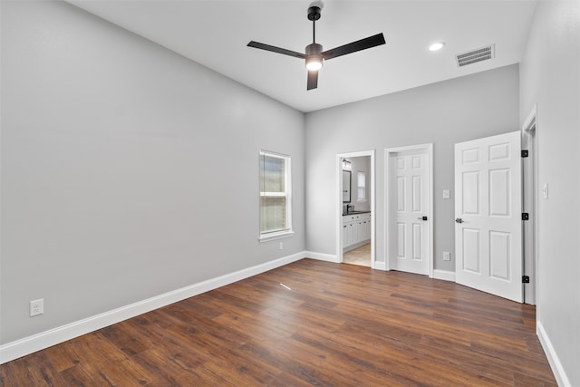 unfurnished bedroom with dark wood-type flooring, a high ceiling, ensuite bath, and ceiling fan