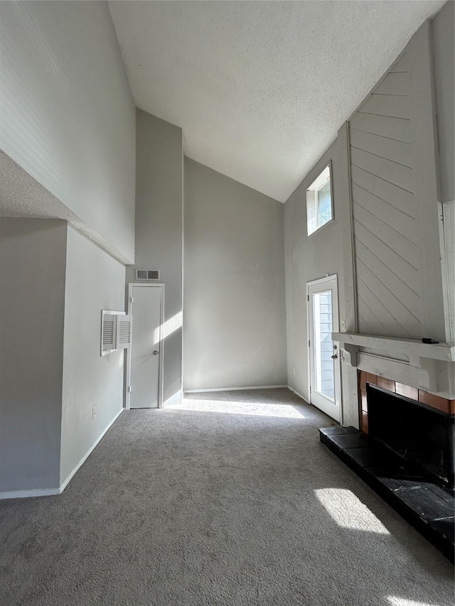 unfurnished living room featuring carpet flooring, a tiled fireplace, high vaulted ceiling, and a textured ceiling