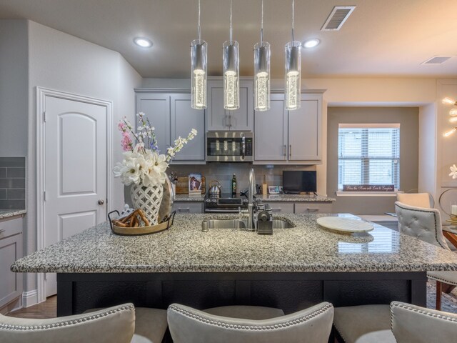 kitchen featuring backsplash, a kitchen breakfast bar, and light stone countertops