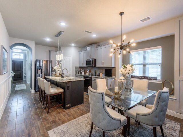 dining space featuring an inviting chandelier, dark hardwood / wood-style floors, and sink