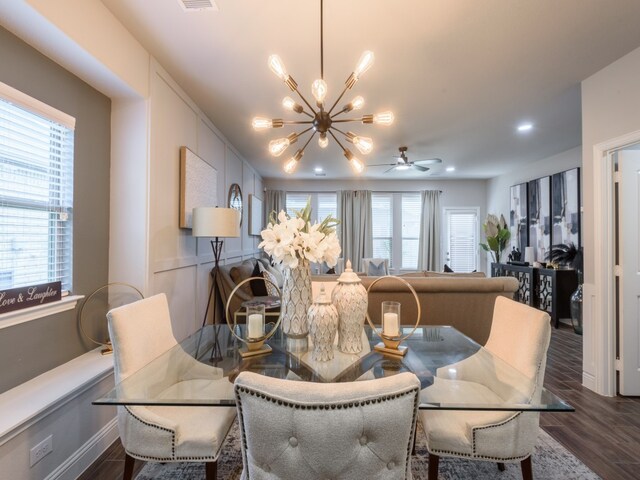 dining area featuring a healthy amount of sunlight, ceiling fan with notable chandelier, and dark wood-type flooring