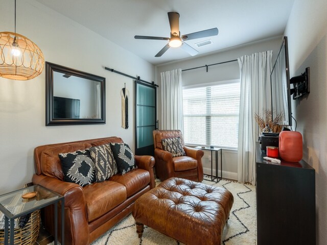 living room with ceiling fan and a barn door