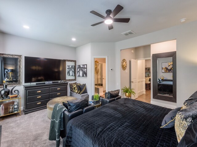 bedroom with connected bathroom, light carpet, and ceiling fan