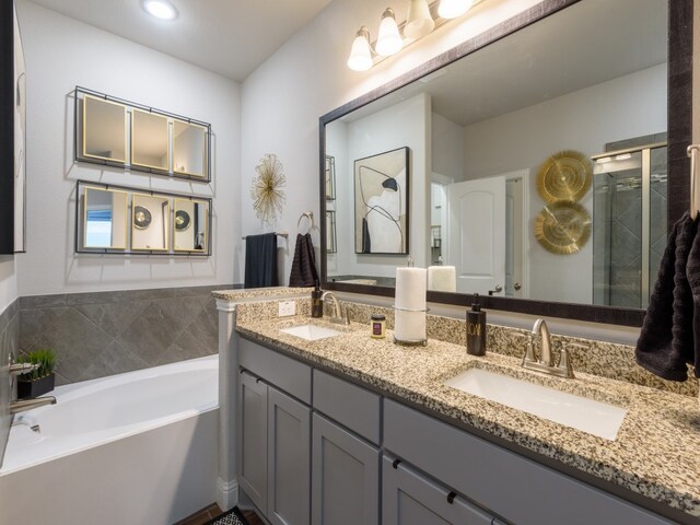 bathroom with dual sinks, a tub, and large vanity