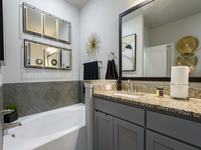 bathroom with oversized vanity and a relaxing tiled bath