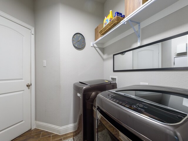 clothes washing area featuring dark tile floors and separate washer and dryer