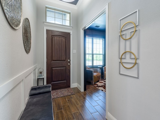 foyer entrance featuring ornamental molding and dark wood-type flooring