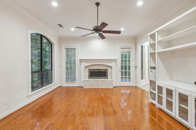 unfurnished living room with ceiling fan, light hardwood / wood-style floors, a healthy amount of sunlight, and a tiled fireplace