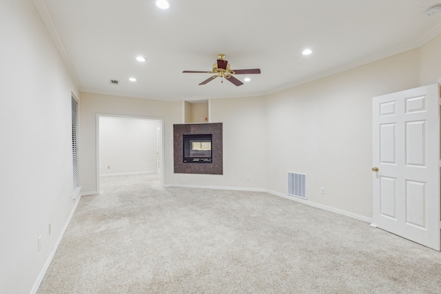 unfurnished living room featuring a multi sided fireplace, ceiling fan, crown molding, and light carpet