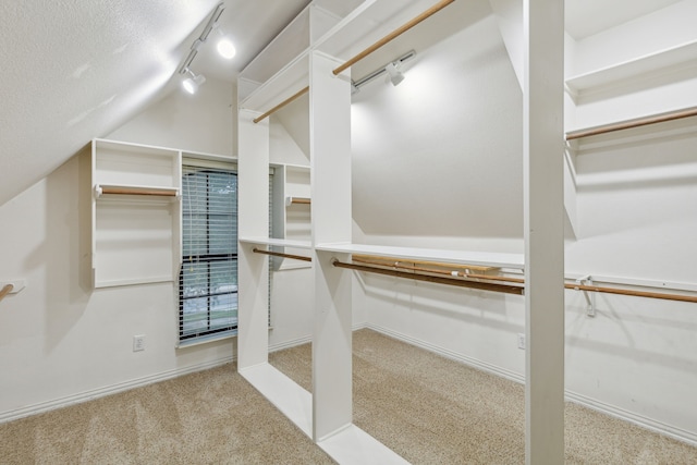 spacious closet with light carpet and vaulted ceiling