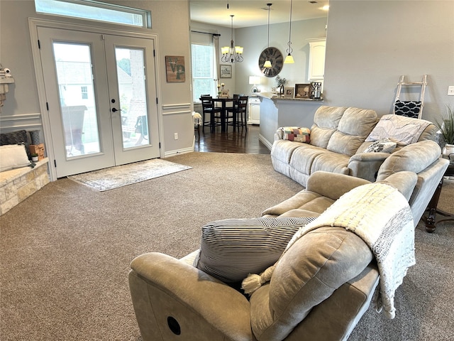 carpeted living room with french doors and an inviting chandelier