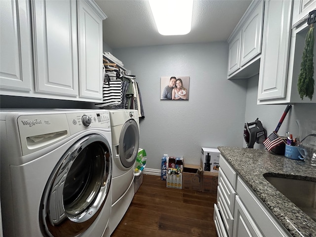 clothes washing area with cabinets, dark hardwood / wood-style flooring, a textured ceiling, sink, and washer and dryer