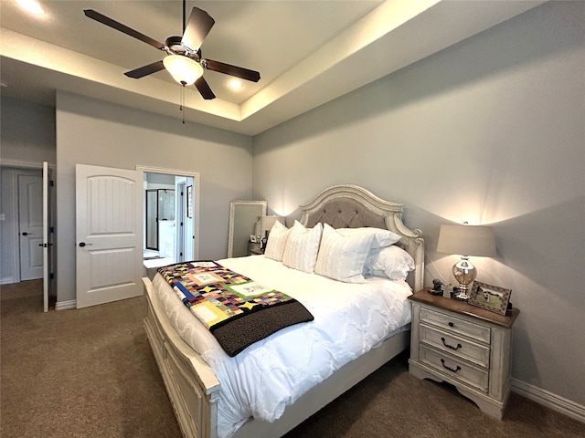 carpeted bedroom featuring ensuite bathroom, ceiling fan, and a tray ceiling