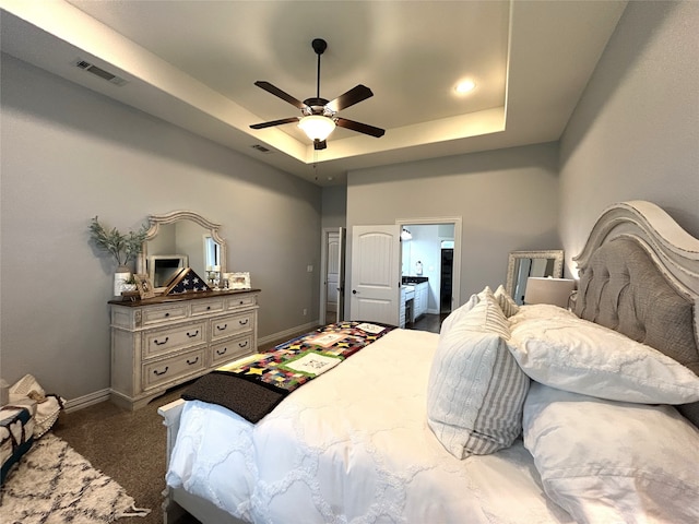 carpeted bedroom with a raised ceiling and ceiling fan