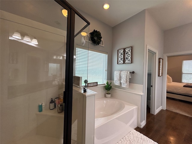 bathroom with hardwood / wood-style floors and independent shower and bath