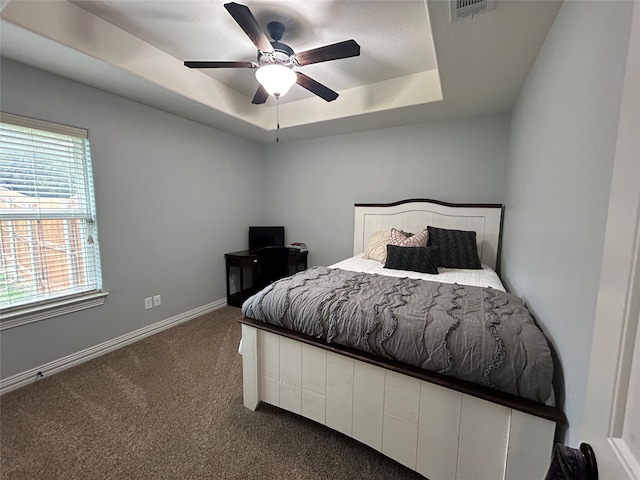 carpeted bedroom featuring a tray ceiling and ceiling fan