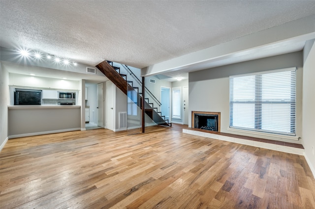 unfurnished living room featuring light hardwood / wood-style floors and a textured ceiling