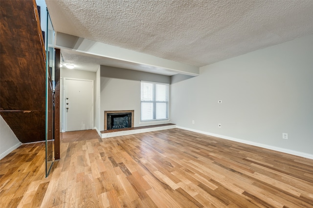 unfurnished living room with light hardwood / wood-style flooring and a textured ceiling