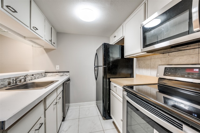 kitchen featuring white cabinets, sink, light tile flooring, tasteful backsplash, and stainless steel appliances