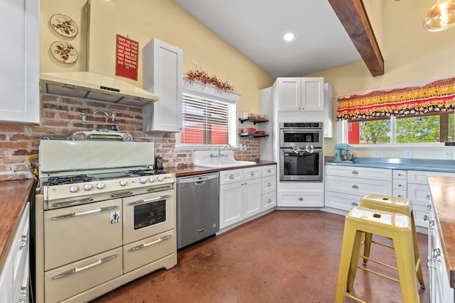 kitchen featuring appliances with stainless steel finishes, plenty of natural light, wall chimney exhaust hood, and beam ceiling