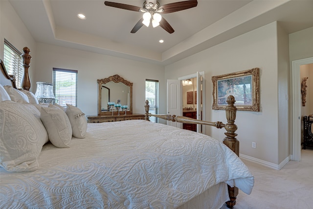 bedroom featuring ceiling fan, carpet flooring, a raised ceiling, and ensuite bathroom