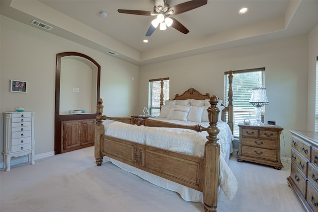 carpeted bedroom with multiple windows, ceiling fan, and a tray ceiling