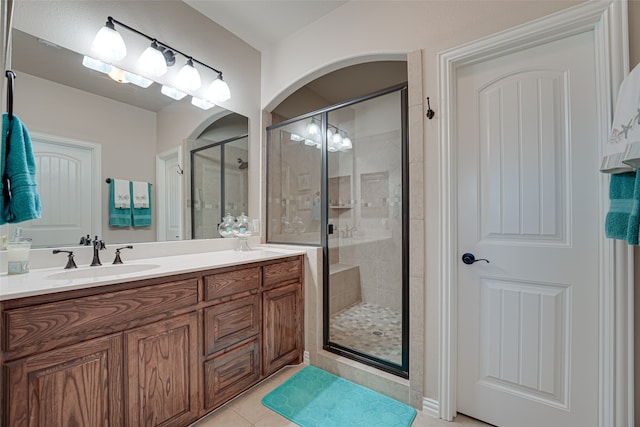 bathroom with tile flooring, large vanity, and a shower with shower door