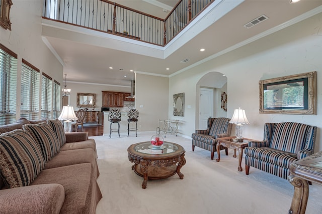 living room featuring ornamental molding, an inviting chandelier, a towering ceiling, and hardwood / wood-style flooring