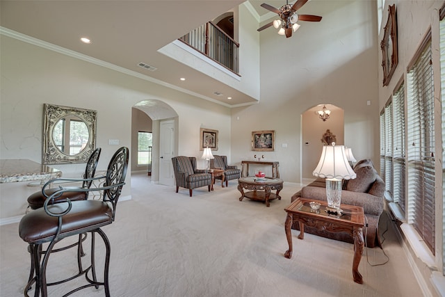 carpeted living room featuring ornamental molding, ceiling fan, and a towering ceiling