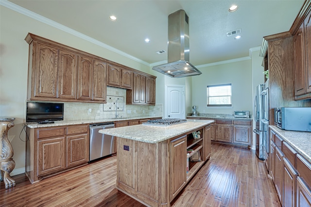 kitchen with a center island, island range hood, ornamental molding, appliances with stainless steel finishes, and light hardwood / wood-style floors