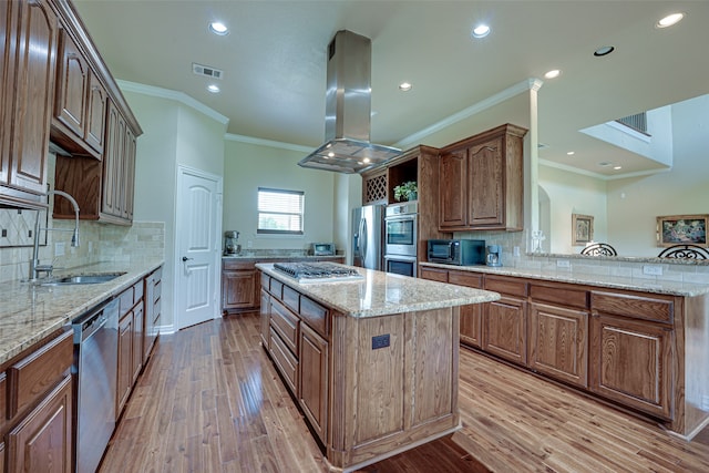 kitchen featuring light stone counters, a kitchen island, backsplash, light wood-type flooring, and island range hood