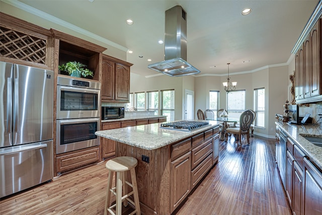 kitchen with backsplash, stainless steel appliances, island exhaust hood, a center island, and light wood-type flooring