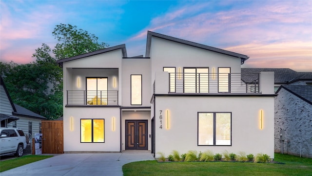 contemporary home featuring a lawn and a balcony