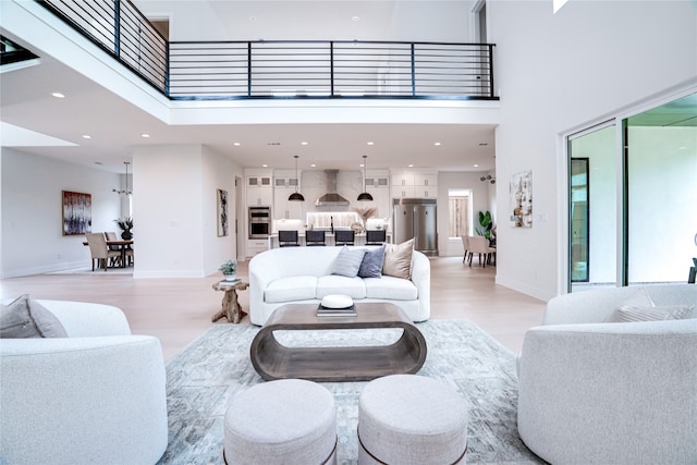 living room featuring light hardwood / wood-style floors, a healthy amount of sunlight, and a towering ceiling