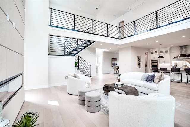 living room featuring a towering ceiling and light hardwood / wood-style floors